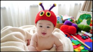 はらぺこあおむしの手作りニット帽を被った笑顔の赤ちゃんと制作道具一式