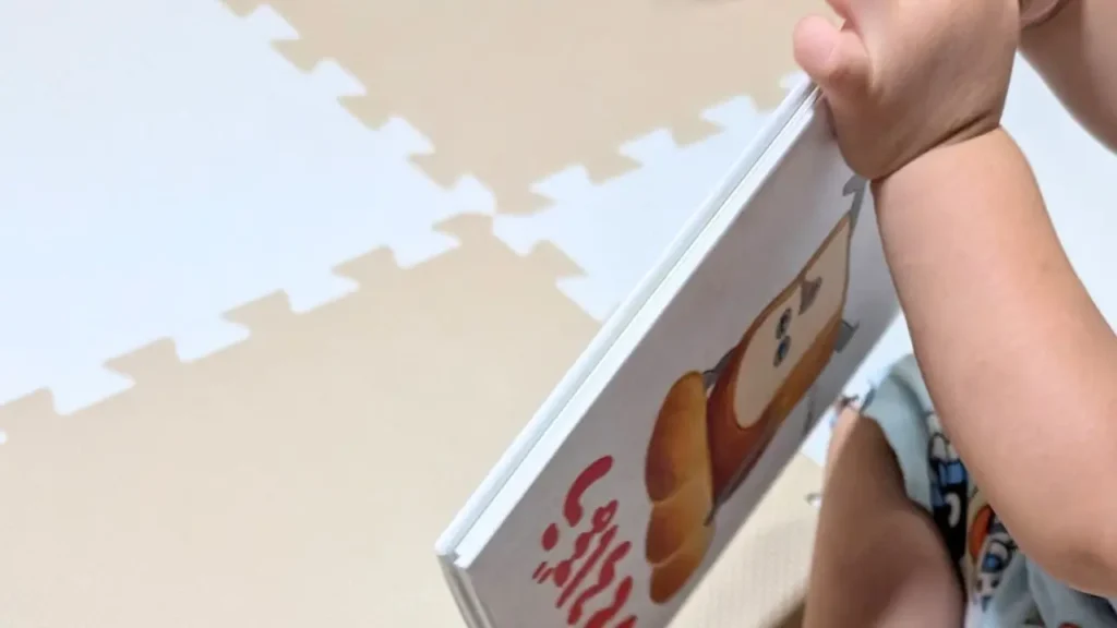 子どもが絵本『パンどろぼう』を立てて持ち、本の厚みが見える様子