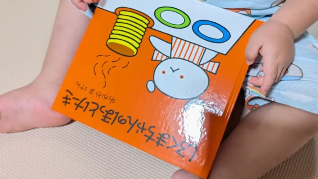 子どもが膝の上で絵本『しろくまちゃんのほっとけーき』を持っている様子