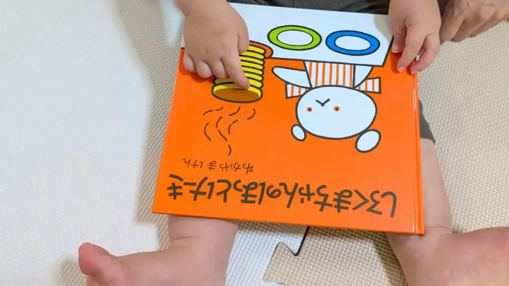 子どもが『しろくまちゃんのほっとけーき』の表紙に描かれたホットケーキを指さす様子