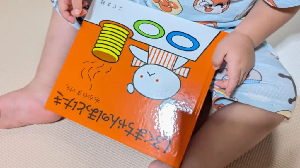 子どもが膝の上で『しろくまちゃんのほっとけーき』を持っている写真